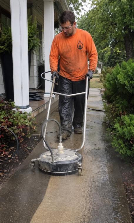 Technician pressure washing a driveway